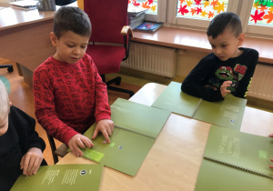 Dzieci wskazują w książkach znaczek produktu ekologicznego.