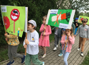 Dzieci maszerują ulicami osiedla z plakatami związanymi z Dniem Bez Tytoniu.